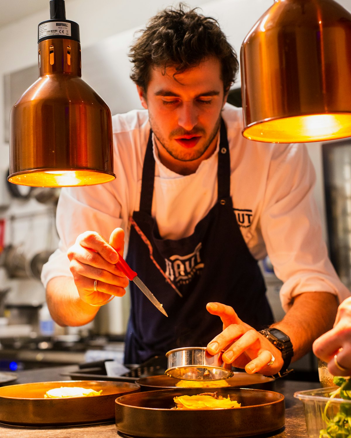 Chef Theo Marchand finishing a plate under the heat lamps